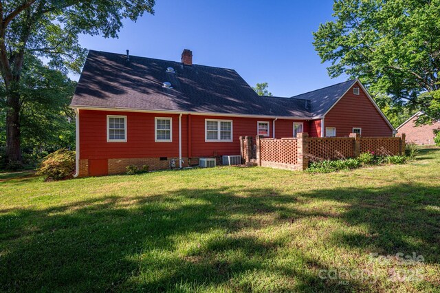 back of house featuring a shingled roof, crawl space, a yard, and a chimney