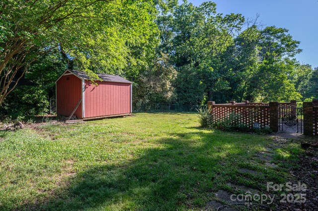 view of yard featuring a storage unit, an outdoor structure, and fence