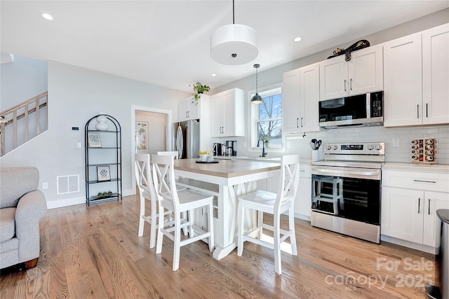 7 Mountain View Ave, Black Mountain, NC 28711 - kitchen featuring stainless steel appliances, light wood-style flooring, a kitchen bar, white cabinets, and recessed lighting