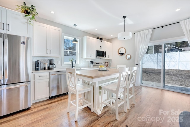 7 Mountain View Ave, Black Mountain, NC 28711 - kitchen with stainless steel appliances, backsplash, light wood finished floors, white cabinets, and decorative light fixtures