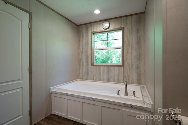bathroom with a bath, wood finished floors, and crown molding