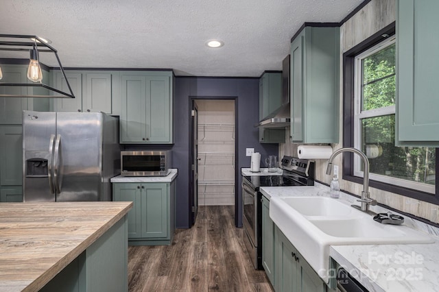kitchen with a sink, stainless steel appliances, a textured ceiling, and dark wood finished floors