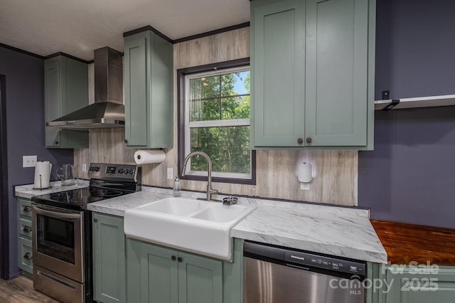 kitchen with appliances with stainless steel finishes, green cabinetry, and wall chimney exhaust hood