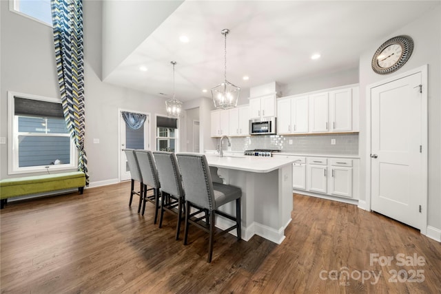 3588 County Down Ave, Kannapolis, NC 28081 - kitchen featuring stainless steel microwave, a chandelier, a center island with sink, a kitchen breakfast bar, and decorative backsplash