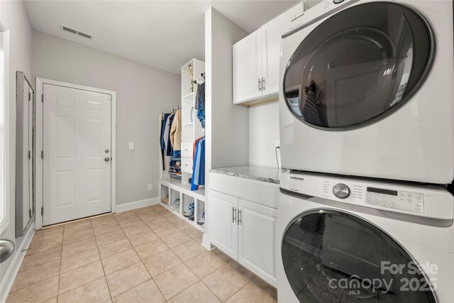 3588 County Down Ave, Kannapolis, NC 28081 - laundry area with stacked washing machine and dryer, cabinet space, light tile patterned floors, and baseboards