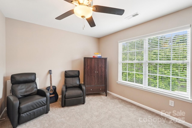 sitting room with baseboards, visible vents, light carpet, and ceiling fan