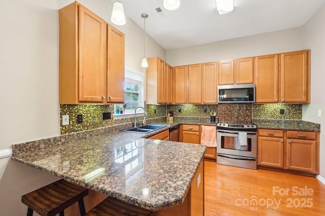 3032 Kilbeggan Dr, Clover, SC 29710 - kitchen featuring appliances with stainless steel finishes, a sink, a peninsula, decorative light fixtures, and light wood-type flooring