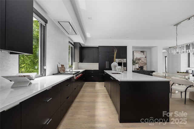 614 Queens Rd, Charlotte, NC 28207 - kitchen featuring modern cabinets, dark cabinetry, light wood-type flooring, stainless steel gas stovetop, and hanging light fixtures