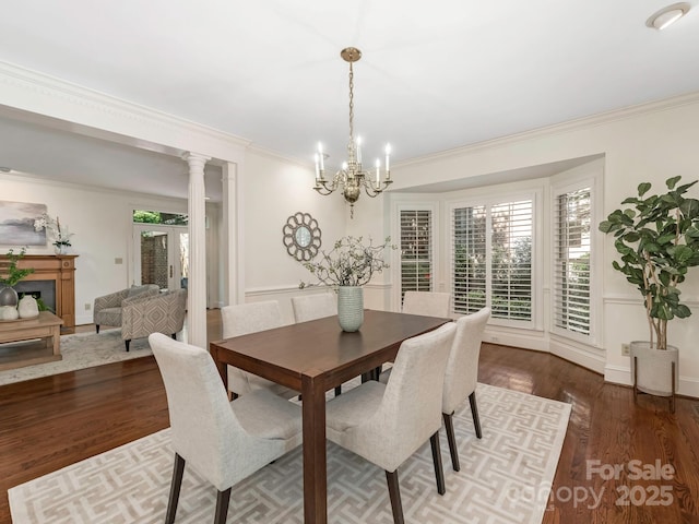232 Perrin Pl, Charlotte, NC 28207 - dining space with ornamental molding, a chandelier, wood finished floors, a fireplace, and decorative columns