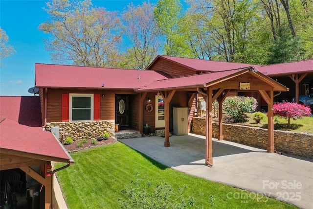 view of front of home featuring a patio, a front lawn, roof with shingles, and stone siding