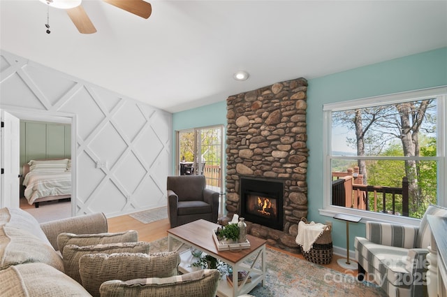 living area featuring baseboards, ceiling fan, wood finished floors, and a fireplace
