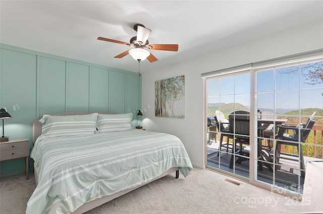 carpeted bedroom featuring visible vents, a ceiling fan, a mountain view, and access to outside