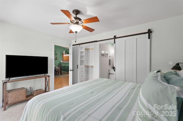 bedroom with ceiling fan, a barn door, and a closet