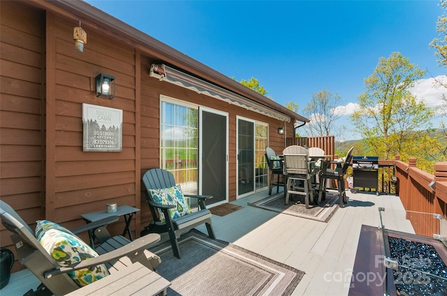 deck with outdoor dining area and an outdoor fire pit