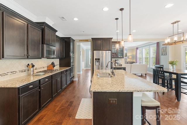 kitchen with a sink, appliances with stainless steel finishes, ornamental molding, and a breakfast bar area