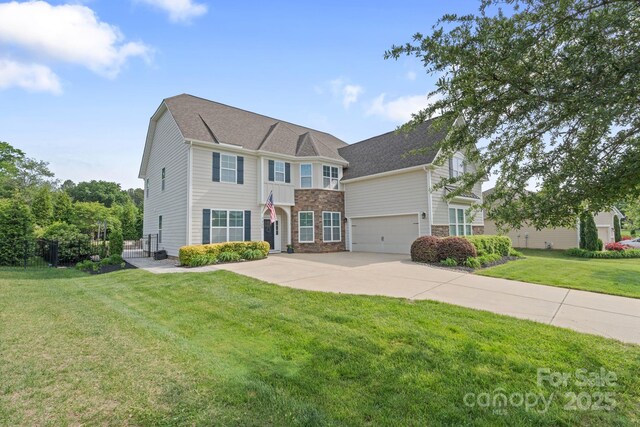 colonial house featuring a shingled roof, driveway, and a front yard