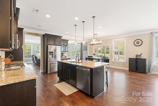 kitchen featuring crown molding, a sink, a center island with sink, and stainless steel appliances