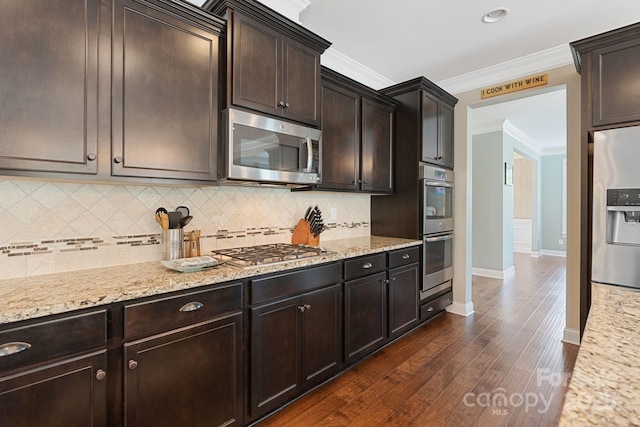 kitchen featuring crown molding, light stone countertops, stainless steel appliances, and backsplash