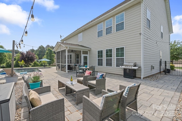 rear view of house featuring a sunroom, outdoor lounge area, a fenced in pool, and a patio