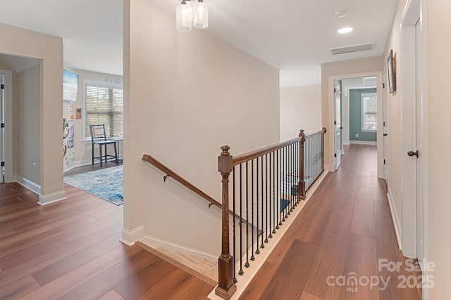 hall featuring an upstairs landing, a wealth of natural light, wood finished floors, and visible vents