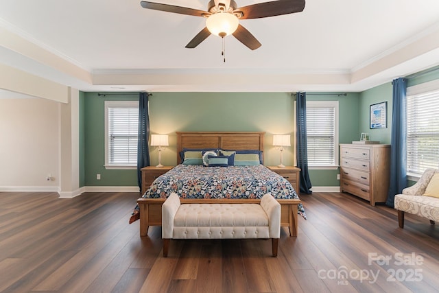 bedroom with multiple windows, a tray ceiling, ornamental molding, and hardwood / wood-style flooring