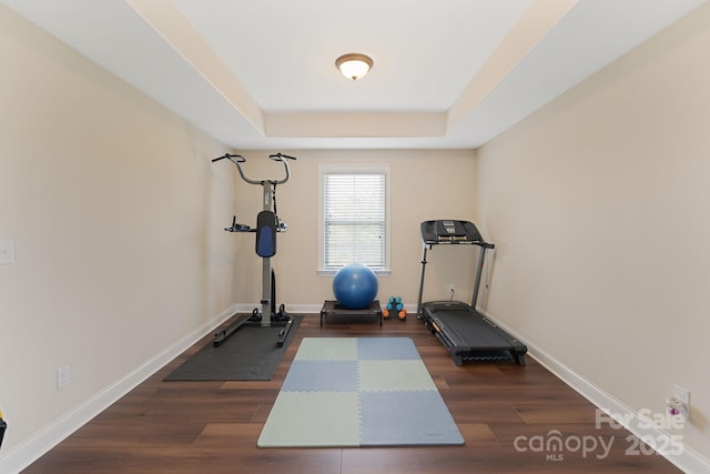 workout area with baseboards, dark wood-style floors, and a raised ceiling