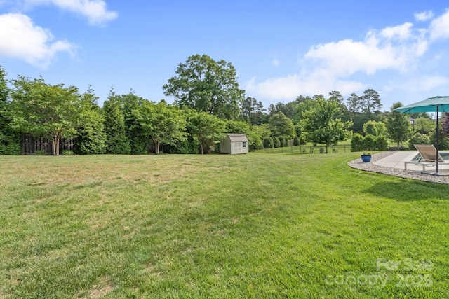 view of yard featuring a patio, an outdoor structure, a shed, and fence