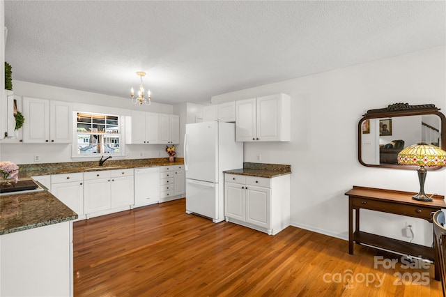 709 Weldon Ln, Salisbury, NC 28146 - kitchen featuring wood finished floors, white appliances, white cabinets, a sink, and a notable chandelier
