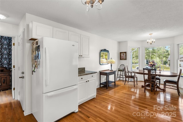 709 Weldon Ln, Salisbury, NC 28146 - kitchen featuring a textured ceiling, freestanding refrigerator, a notable chandelier, light wood-style floors, and white cabinetry