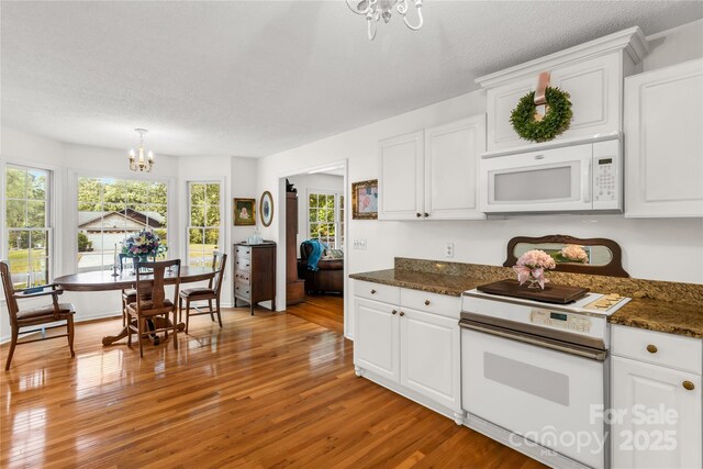 709 Weldon Ln, Salisbury, NC 28146 - kitchen with white microwave, electric range, light wood-style flooring, and a chandelier