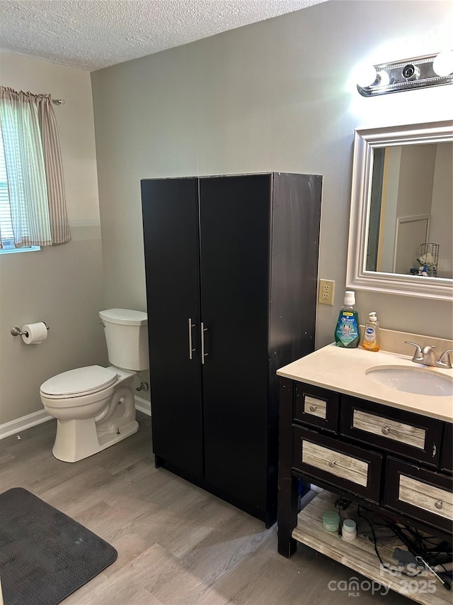 bathroom with vanity, a textured ceiling, toilet, and wood finished floors