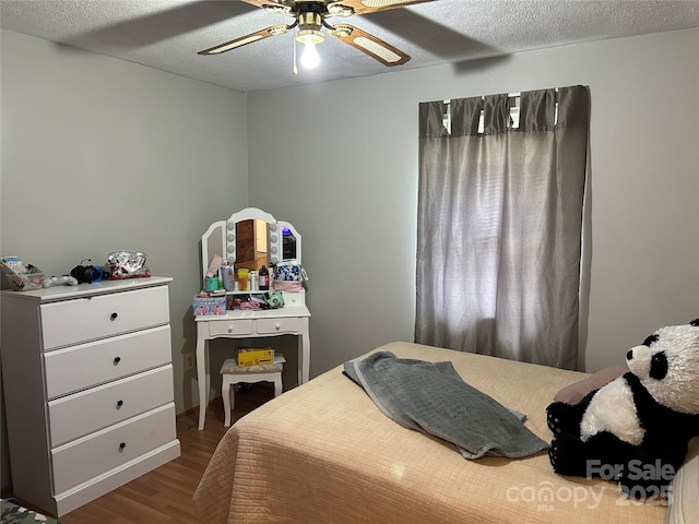 bedroom with a ceiling fan, a textured ceiling, and wood finished floors