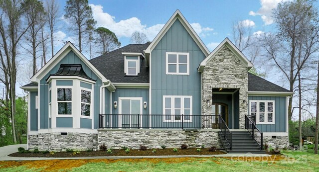 view of front of property with roof with shingles, board and batten siding, stone siding, and crawl space