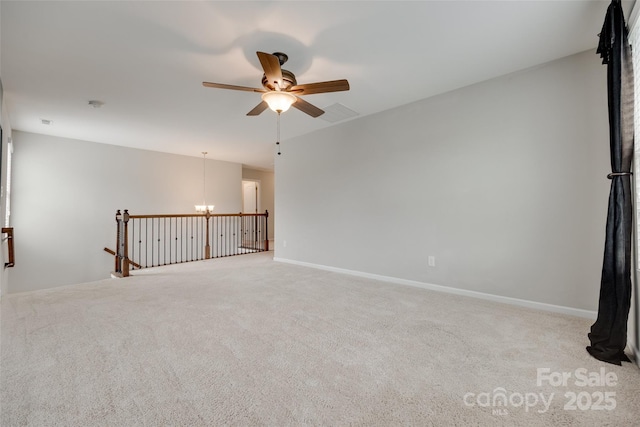 carpeted empty room featuring ceiling fan with notable chandelier
