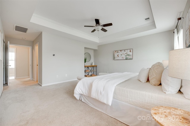 bedroom featuring light colored carpet, a tray ceiling, and visible vents