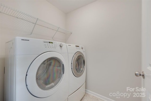 washroom with light tile patterned floors, laundry area, washing machine and dryer, and baseboards