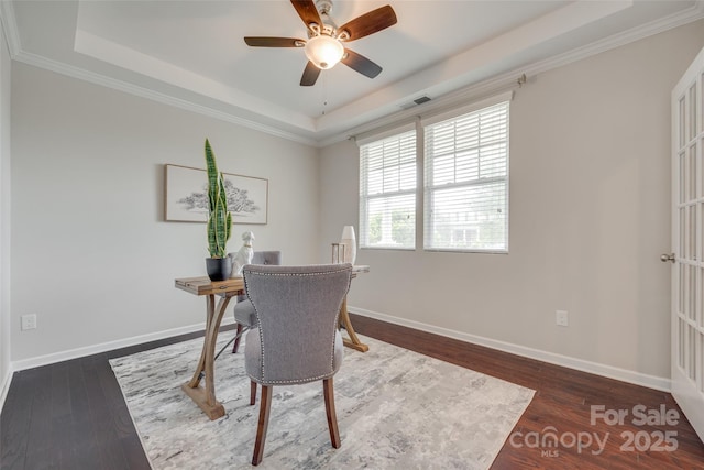 office with visible vents, wood finished floors, baseboards, a tray ceiling, and a ceiling fan