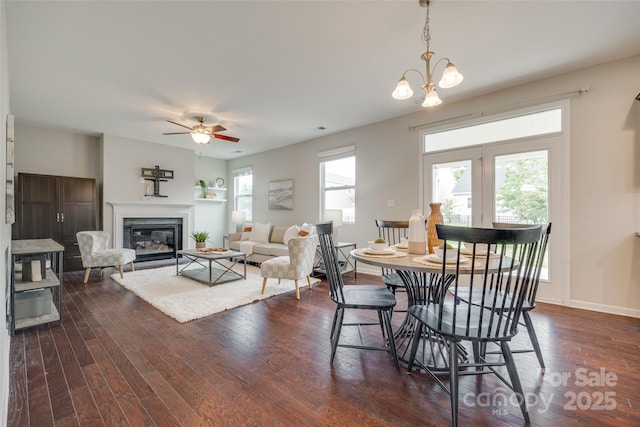 dining room featuring a glass covered fireplace, baseboards, ceiling fan, and dark wood-style flooring