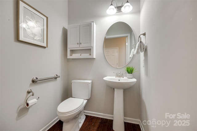 bathroom featuring baseboards, a sink, wood finished floors, and toilet