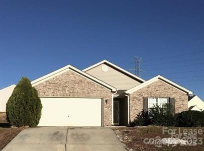 single story home with an attached garage, concrete driveway, and stone siding