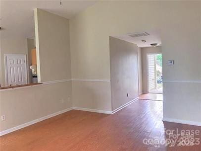spare room featuring baseboards, visible vents, and wood finished floors
