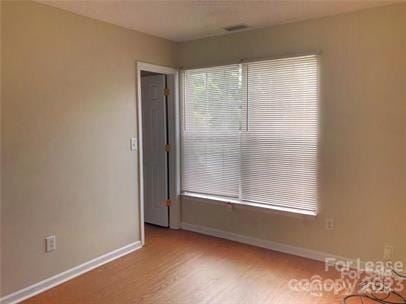 spare room with baseboards and wood finished floors