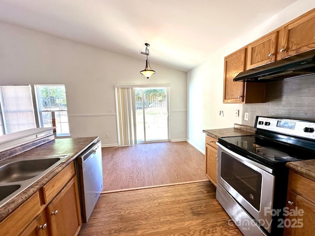 8551 Appledale Dr, Charlotte, NC 28262 - kitchen with appliances with stainless steel finishes, under cabinet range hood, vaulted ceiling, brown cabinetry, and dark countertops