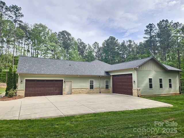 view of front of property featuring stone siding, board and batten siding, a front yard, concrete driveway, and an attached garage