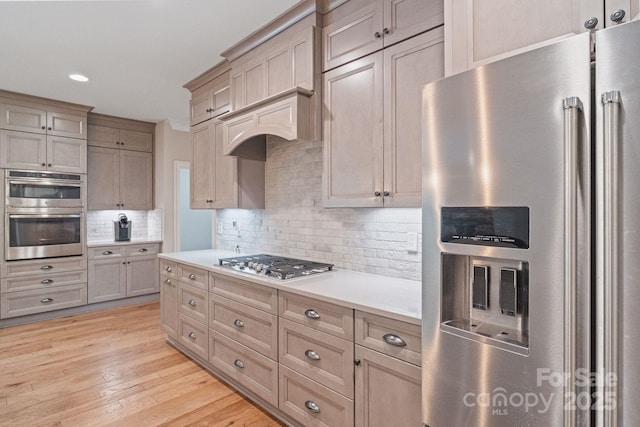 kitchen featuring stainless steel appliances, light countertops, decorative backsplash, light wood-style flooring, and recessed lighting