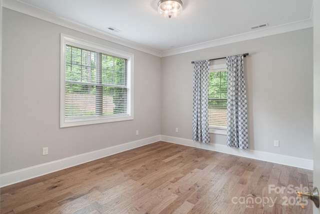 empty room featuring ornamental molding, wood finished floors, and baseboards