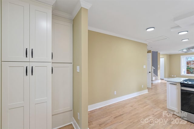 kitchen with stainless steel electric range oven, crown molding, light wood-style flooring, and baseboards