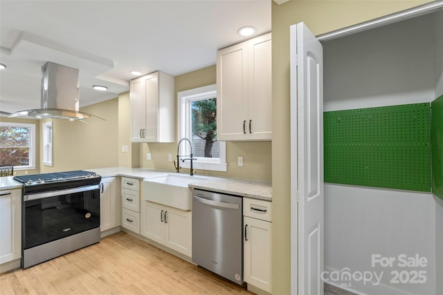 kitchen featuring a wealth of natural light, island exhaust hood, stainless steel appliances, and a sink
