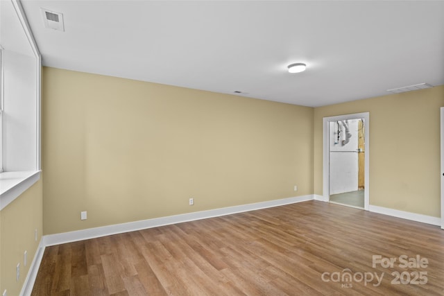 interior space with baseboards, visible vents, and wood finished floors
