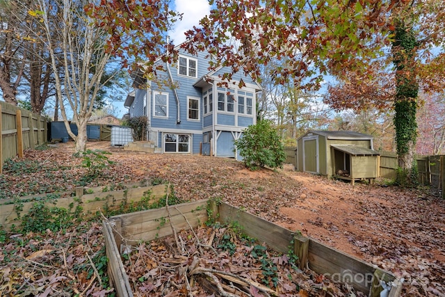rear view of house with a storage unit, a garden, an outbuilding, and a fenced backyard